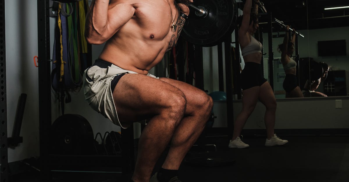 A shirtless man lifts weights during an intense gym workout, showcasing strength and fitness.